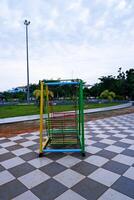 hanging swing chair that is usually found in parks or playgrounds. hanging swing chair made of iron with a combination of yellow, green, and red colors. photo