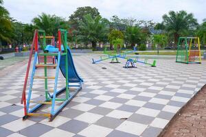 a playground in the park consisting of slides, seesaws, and hanging chairs. photo