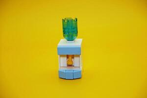 mini dispenser toy assembled from plastic blocks. dispenser toy isolated on yellow background. photo