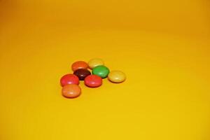 chocolate balls coated with colorful candy. colorful chocolate candy isolated on yellow background. photo