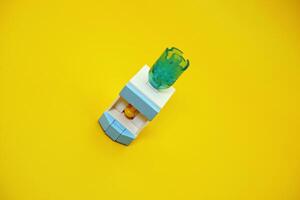 mini dispenser toy assembled from plastic blocks. dispenser toy isolated on yellow background. photo