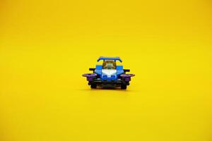 blue racing car assembled from plastic blocks. toy car isolated on yellow background photo