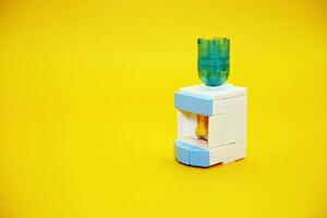 mini dispenser toy assembled from plastic blocks. dispenser toy isolated on yellow background. photo