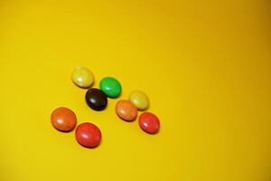 chocolate balls coated with colorful candy. colorful chocolate candy isolated on yellow background. photo