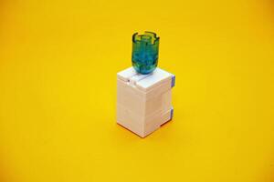 mini dispenser toy assembled from plastic blocks. dispenser toy isolated on yellow background. photo