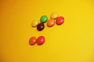 chocolate balls coated with colorful candy. colorful chocolate candy isolated on yellow background. photo