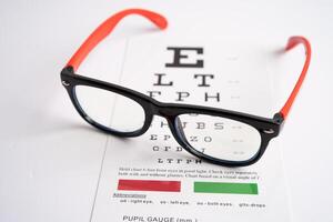 Glasses on eye testing exam chart to check eyesight accuracy of reading. photo