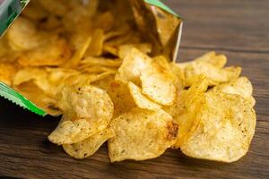 Potato chips, delicious spicy for crips, thin slice deep fried snack fast food in open bag. photo