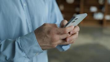 Side view unknown young Caucasian man businessman user male hands hold mobile cell phone typing message smartphone texting ordering delivery play game shopping online gadget use remote chat app indoor photo