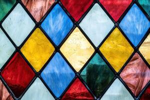 A vibrant stained glass window featuring an intricate Argyle pattern with geometric shapes and vivid colors photo