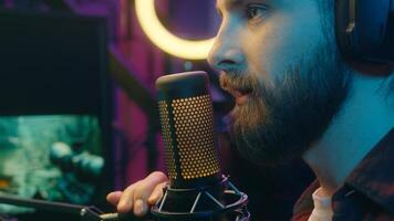 Happy Caucasian man carefree gamer male guy influencer in headphones cyber sport radio blogger talking in microphone stream online on Internet broadcast content home neon popular streamer speak smile photo