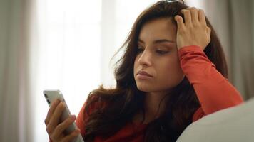 Bored sad Caucasian upset woman lazy female girl unhappy client user scrolling mobile phone smartphone browsing social media online app on couch burnout problems boredom depression indoors home room photo