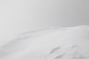 Minimalist Winter Landscape featuring Vast expanse of gently rolling Snowcovered Hills partially obscured by a soft mist. Solitary distant object adds focal point, creating serene and tranquil scene photo