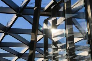 Modern Architectural Design showcasing intricate Geometric Patterns and Glass divisions, accentuated Sunlight reflection. Combination metal racks and glass Partitions reflects through blue sky photo