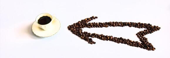 An arrow of coffee beans points in the right direction to a cup of coffee. photo