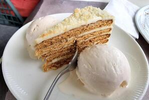 Close up of a delicate piece of cake and ice cream,on a plate with a fork photo