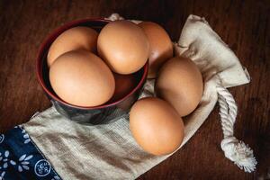 Eggs in the little bowl on the white cloth bag as wooden background for cooking with new recipe photo