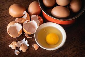 Broken egg shells and eggs on tray at wooden background photo