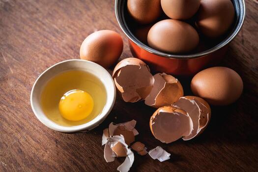 Broken egg shells and eggs on tray at wooden background photo