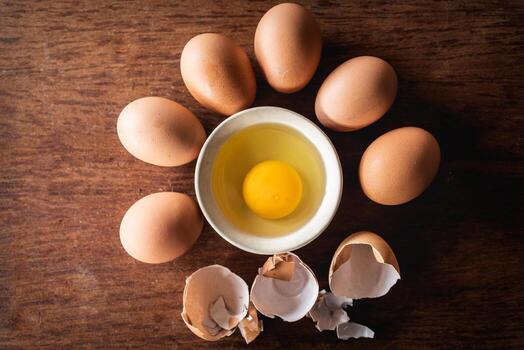 Broken egg shells and eggs on tray at wooden background photo
