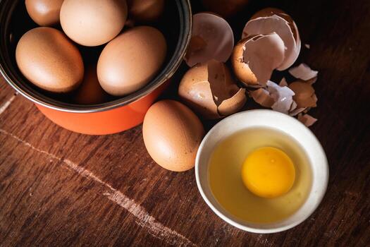 Broken egg shells and eggs on tray at wooden background photo