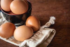 Eggs in the little bowl on the white cloth bag as wooden background for cooking with new recipe photo