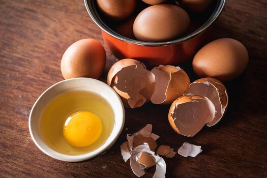 Broken egg shells and eggs on tray at wooden background photo
