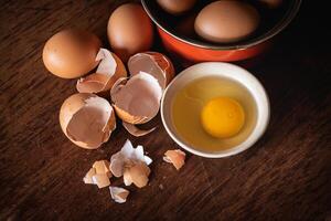 Broken egg shells and eggs on tray at wooden background photo