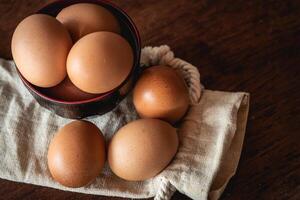Eggs in the little bowl on the white cloth bag as wooden background for cooking with new recipe photo