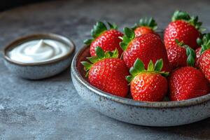 Freshly picked strawberries served in a bowl with dipping cream on a rustic tabletop photo