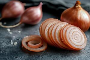 Sliced shallots arranged artistically on a dark stone background with whole shallots in the background during daylight photo