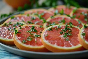 Freshly sliced grapefruit with herbs garnishing served on a light gray plate at a kitchen table photo