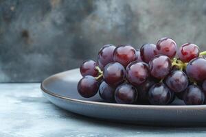Fresh red grapes in a dark plate on a textured surface, showcasing natural colors and freshness photo