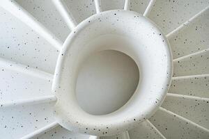 Modern spiral staircase design featuring smooth white contours and subtle speckling, showcasing innovative architecture and aesthetic appeal photo