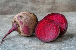 Freshly harvested beetroot with vibrant red slices displayed on a textured gray surface highlighting its natural color and freshness photo