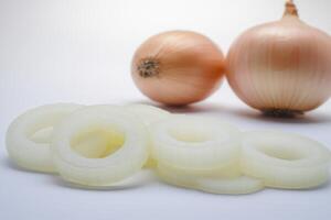 Freshly sliced white onions with whole yellow onions on a clean surface in bright lighting during daytime photo