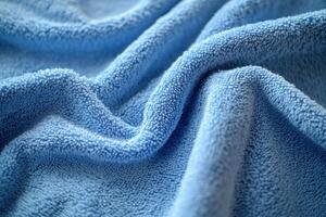 Soft blue fabric drapes in gentle folds on a textured surface illuminated by natural light photo