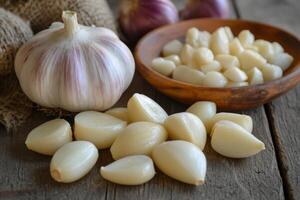 Fresh garlic bulbs and peeled cloves arranged on a rustic wooden table with a bowl of chopped garlic on the side photo