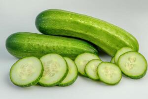 Fresh green cucumbers cut into slices resting on a clean surface, showcasing their vibrant color and crisp texture photo
