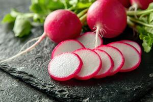 Freshly sliced radishes on a dark stone background in a bright kitchen setting showcasing vibrant colors and textures photo