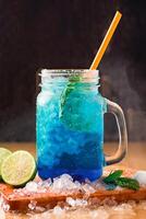 BLUE LAGOON MOJITO Soda with Mint and Lime served in jar with straw isolated on wooden board side view of perfect drink for a hot summer day photo