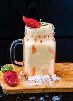 Strawberry Banana Smoothie with Yogurt and Honey served in jar isolated on wooden board closeup side view of healthy drink photo