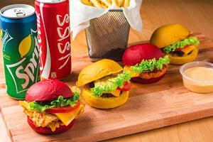 Mini Sliders Combo with Fries, dip sauce and Drinks coke and sprite cans isolated on wooden board side view of fast food meal photo