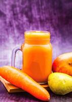 Mixed Carrot, Mango and Pear Smoothie served in mug isolated on wooden board closeup side view of antioxidant juice photo
