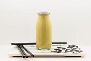 Cold Spanish Latte with Coffee Beans served in a Glass Bottle isolated on wooden board side view of cold beverage on white background photo