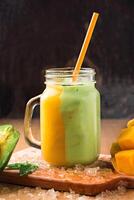 Mango Avocado Smoothie served in jar isolated on wooden board closeup side view of healthy juice photo