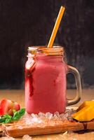 Strawberry Mango Smoothie with Chocolate Drizzle and Mint or Mahara served in jar isolated on wooden board closeup side view of healthy drink photo
