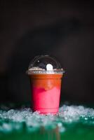 Pink Latte Cold Coffee with crushed ice served in plastic cup isolated on dark background side view of cold beverage drink photo