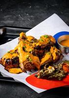 Grilled Peri Peri Chicken with Creamy Sauce and Crispy Garnish served in tray isolated on grey background closeup side view of A la carte meat Food platter photo