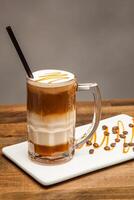 Iced Caramel Macchiato with Whipped Cream and Drizzle caramel sauce served in jar isolated on wooden table side view of cafe dessert drink photo
